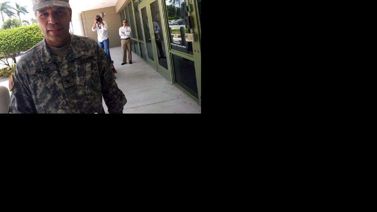 Carol Rosenberg used a finger swipe on Google Glass to capture this scene of being photographed by the  Miami Herald's Patrick Farrell on Thursday, Aug. 8, 2013. In the foreground, Army Col. Gregory Julian, public affairs officer at the U.S. Southern Command. In the rear, Southcom's Ray Sarracino, arms crossed, looks on just outside the Herald's headquarters.