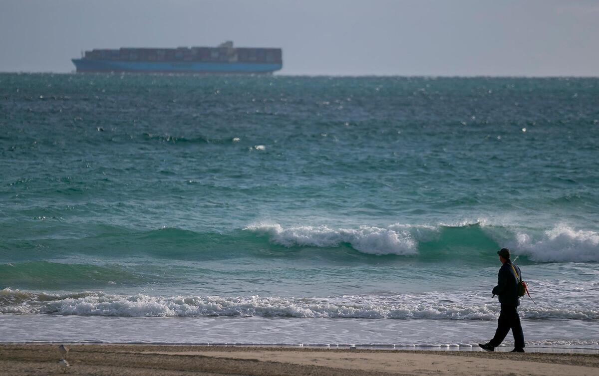 A man walks near the shoreline in Miami Beach as temperatures dip into the low 50s across South Florida on Saturday, January 29, 2022.