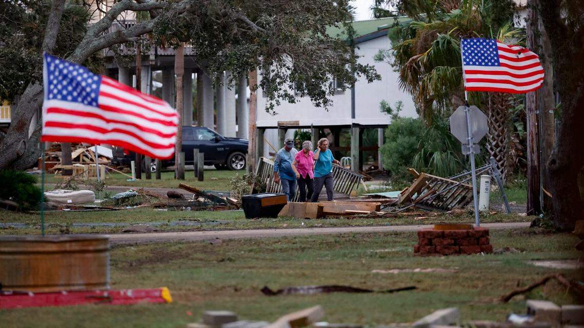 A group of people walk through debris left by Hurricane Idalia in Horseshoe Beach, Florida on Wednesday, August 30, 2023.