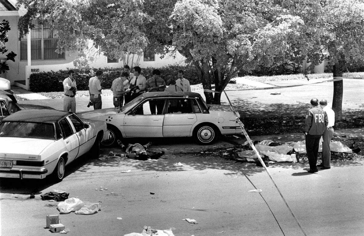 Bodies lie near wrecked, bullet-scarred cars in suburban Kendall after gun battle between FBI agents and two robbery suspects. Both suspects and two FBI agents died on April 11, 1986.