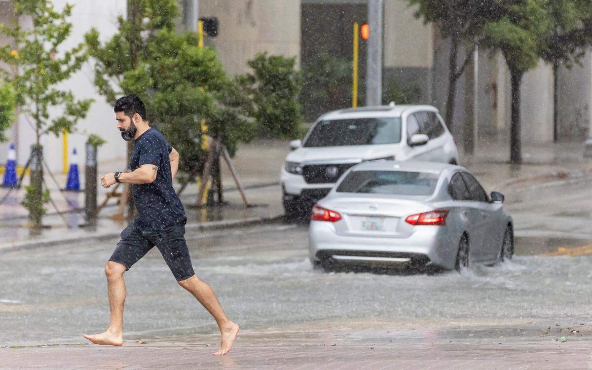 A man is seen running on Biscayne Boulevard as lightning and heavy rain falls over the area on Monday, June 19, 2023, in downtown Miami, Fla.