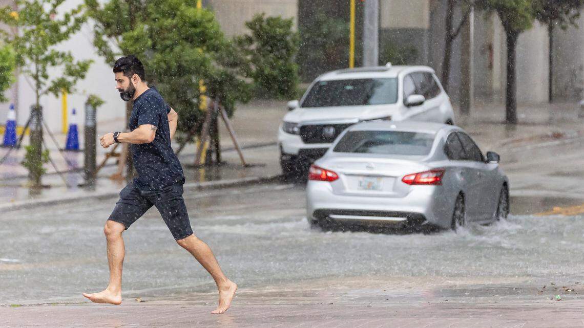 A man runs across Biscayne Boulevard as lightning and heavy rain fall over the area on Monday, June 19, 2023, in downtown Miami, Fla.