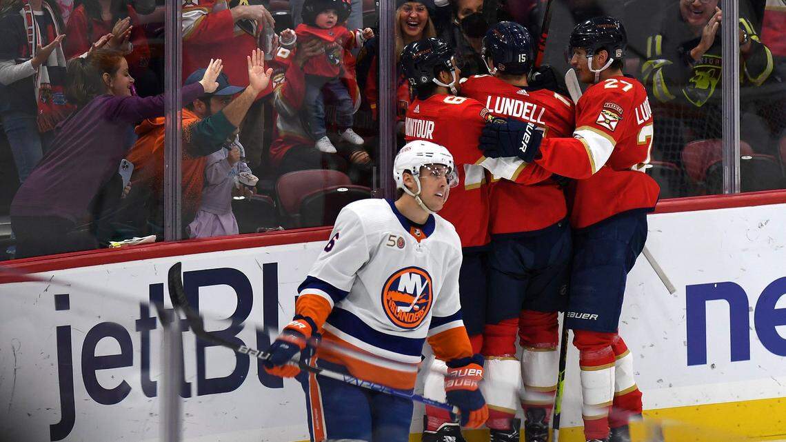 Florida Panthers’ Anton Lundell (15) celebrates with teammates and fans after scoring a goal as New York Islanders’ Ryan Pulock, foreground, skates past during the first period of an NHL hockey game, Sunday, Oct. 23, 2022, in Sunrise, Fla.