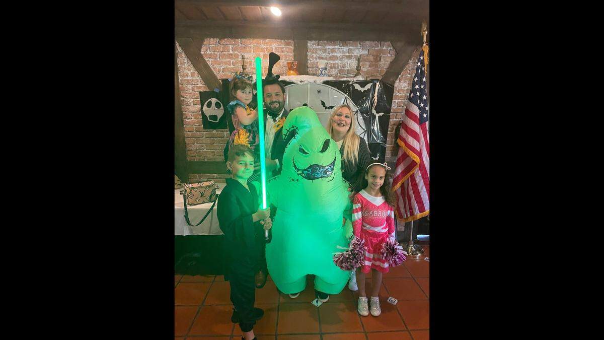 Zoe Martos held by her dad Edward Martos has fun at the “Nightmare Before Christmas Luncheon” with Tarah Rogowski Martos, Sebastian Perez, Harrison Martos in the green Oogie Boogie costume, and Andrea Pedreira. The event launched a toy drive by the Miami Buena Vista Biltmore Lions Club.
