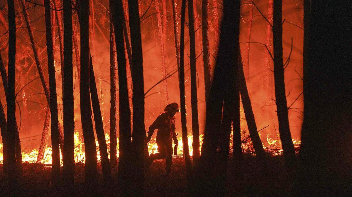 A firefighter is silhouetted against a fire burning outside village of Roqueiro, near Oleiros, Portugal in September 2020.