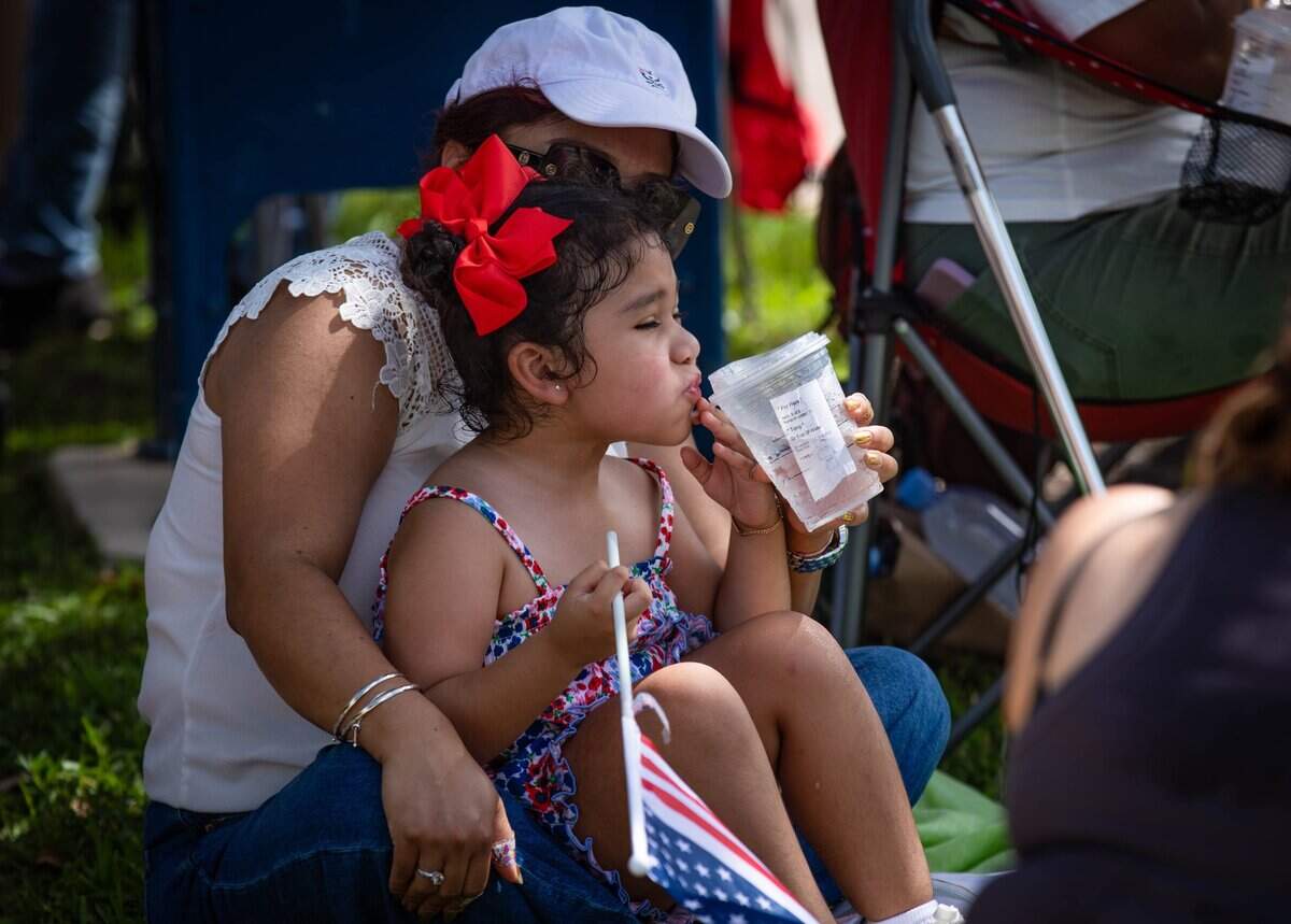 Sury Fuentes helps her daughter Keyla Santalla hydrate on Thursday, July 4, 2024 at the Key Biscayne Fourth of July Parade.