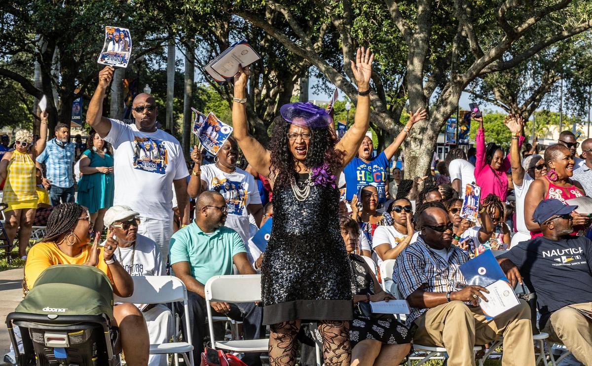 Gina Moorman (center) stood up proudly with both of her hands raised when Florida Memorial University President Jaffus Hardrick asked the graduates’ relatives to stand up during the spring commencement ceremony in Miami Gardens, on Saturday May 6, 2023. Moorman, from Detroit, said her only son, Adonis Lockett, 22, got a degree in criminal justice and wants to launch a career in crime scene investigations. “I already cried. I’m so emotional,” she said. “He worked a lot to get here.”