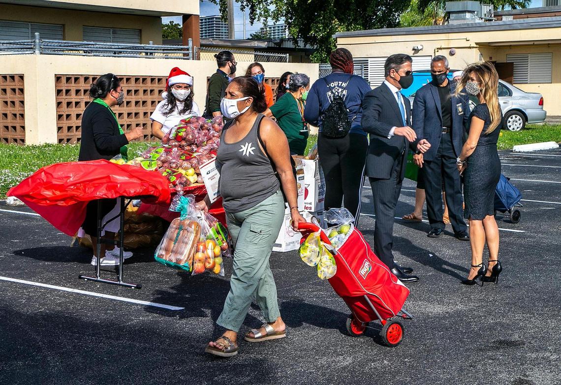 Norma Martinez walks with her cart full of groceries, near Alberto Carvalho, superintendent of Miami-Dade County Schools, during a food drive at Citrus Grove Elementary on Wednesday.