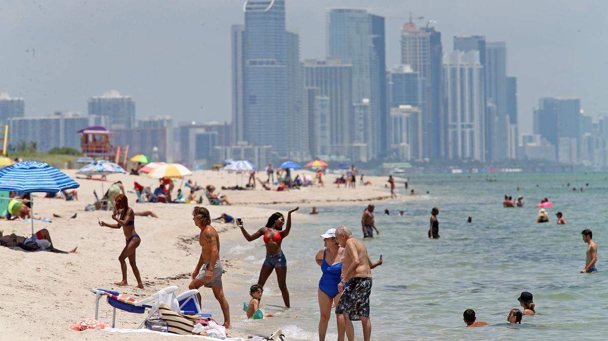 Beachgoers escape the heat on the beach on the shore line on Miami Beach in July. Florida saw tourism numbers crash more than 60 percent in the second quarter of the year from the same period in 2019, ending a decade of year-after-year growth of travelers to Florida.