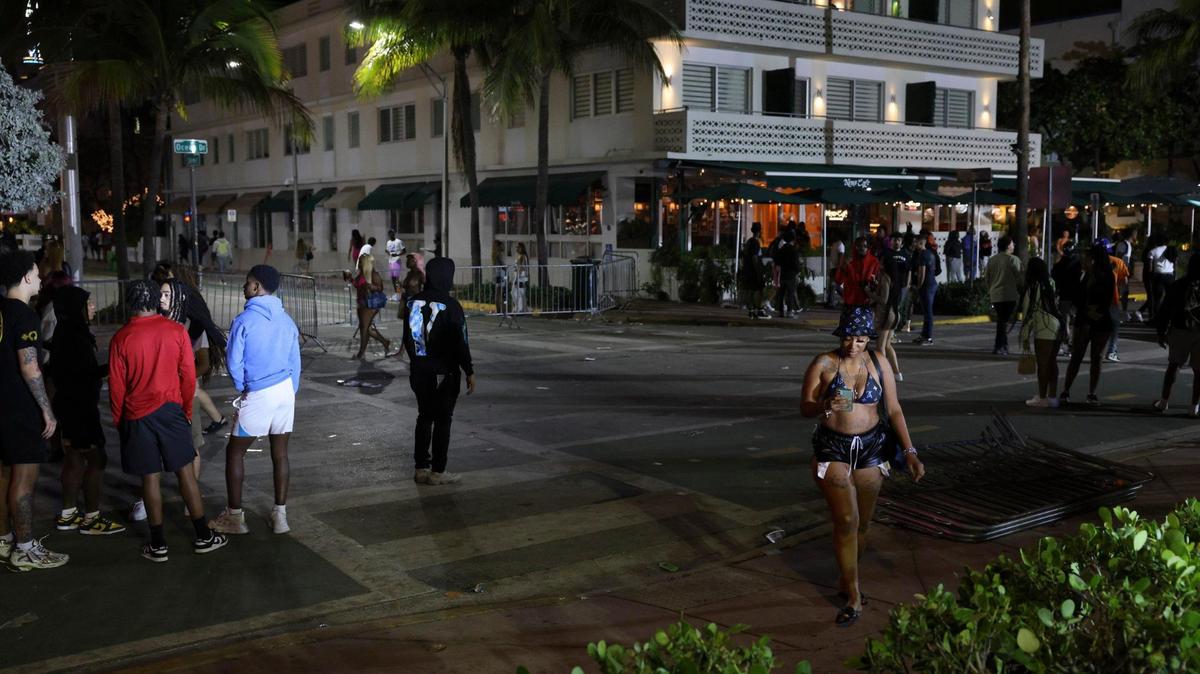 People clear out at the corner of Eighth Street and Ocean Drive after police announce a brief curfew Sunday night after a pair of deadly shootings over the spring break on Miami Beach.