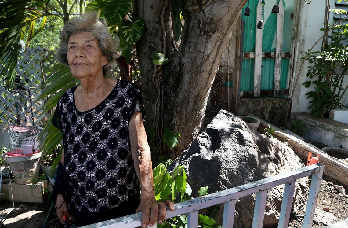 Basilia Quiles Cruz, 79, stands next to a rock that fell from the mountains 80 years ago. She has decided to stay in the home where she grew up in the Abras neighborhood, although many nearby houses have been damaged by several earthquakes in the southern town of Guánica, Puerto Rico.