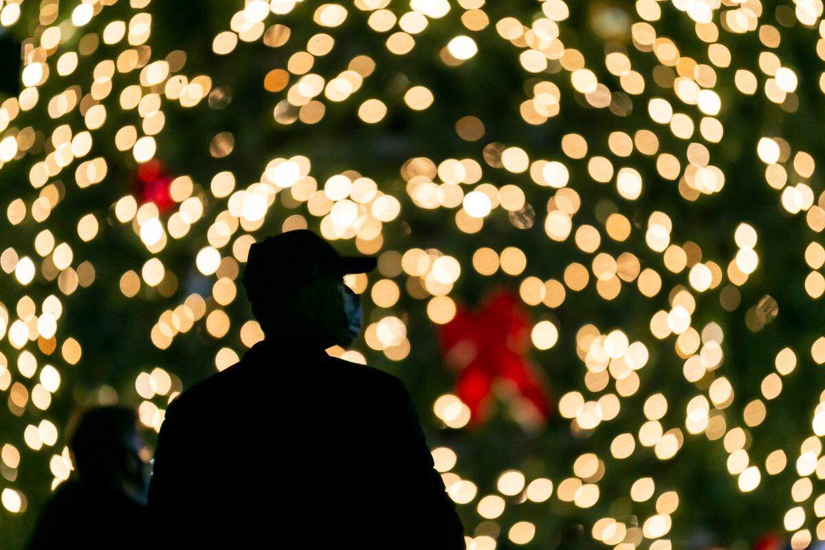 People gather to watch a holiday tree lighting ceremony in downtown MiamiÕs Bayfront Park on Monday, December 7, 2020. The tree, created by Christmas Designers, Inc., is an artificial, 50-foot Rocky Mountain Pine Tree adorned with a custom lighting package. It will stay lit every night and remain in the park through the New Year.
