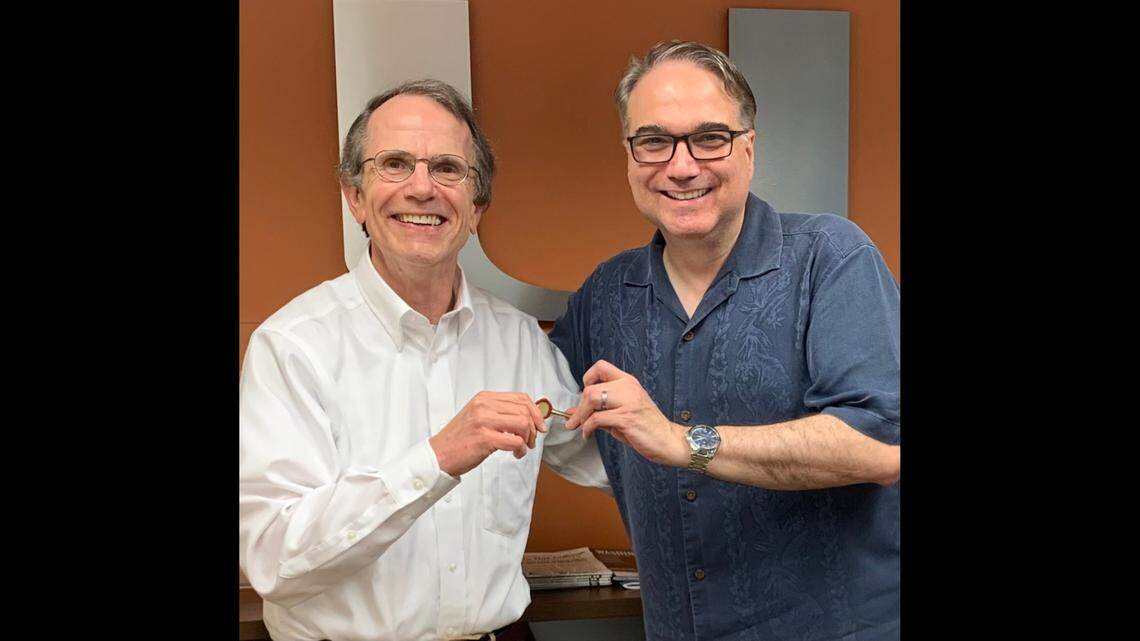 Newly appointed UM law school acting dean Steve Schnably, left, takes a key from Anthony Varona, the dean of UM law school whom UM President Julio Frenk fired last month as dean. Varona’s last day as dean was Wednesday, June 30, 2021. Varona shared the photo in a tweet at 5 p.m. Wednesday.