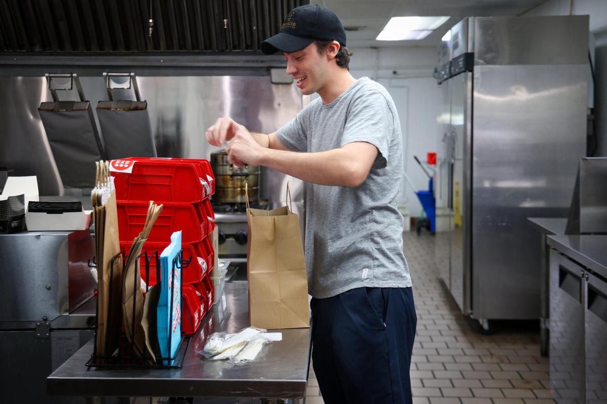 Cem Kinay prepares an order to be picked up after it was cooked by the robotic chef from Better Days. The business serves the surrounding neighborhood and offices with takeout and delivery.