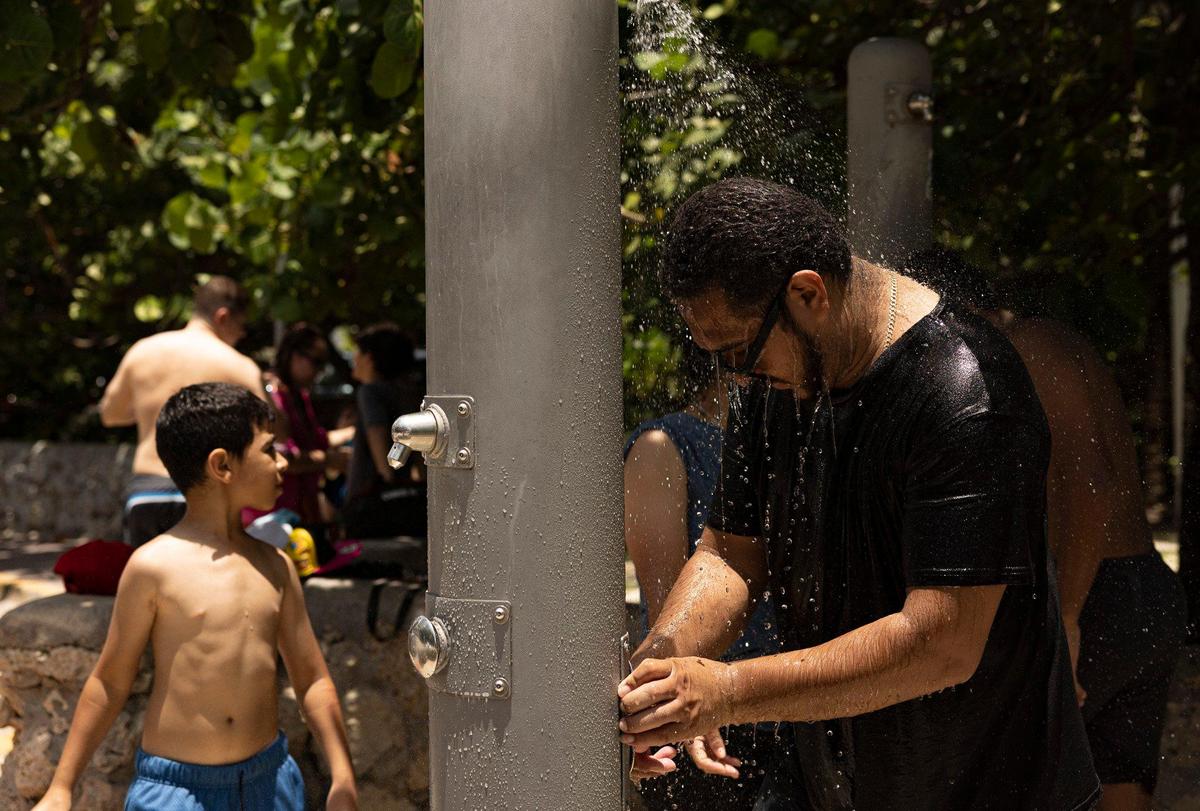 A man rinses off with his family during a day over 90 degrees on Thursday, July 13, 2023, in South Beach.