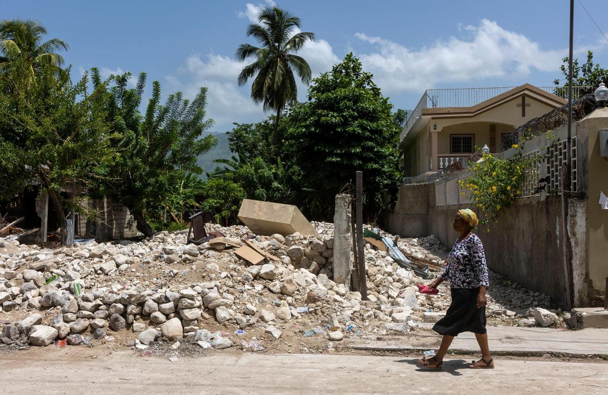 A woman walks by the earthquake rubble of a house in the town of Maniche in southwestern Haiti on Aug. 23, 2021.
