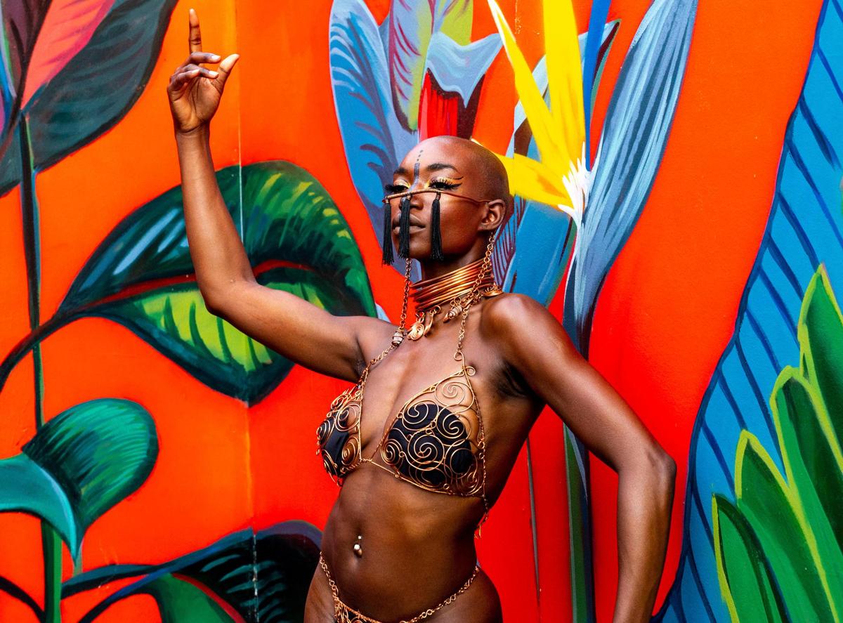 Festival goer Iyanna James-Stephenson poses in front of the artwork of her friend, Terrea Armsting, 24, during AFROPUNK music festival at The Urban in the Historic Overtown neighborhood of Miami, Florida, on Saturday, May 21, 2022.
