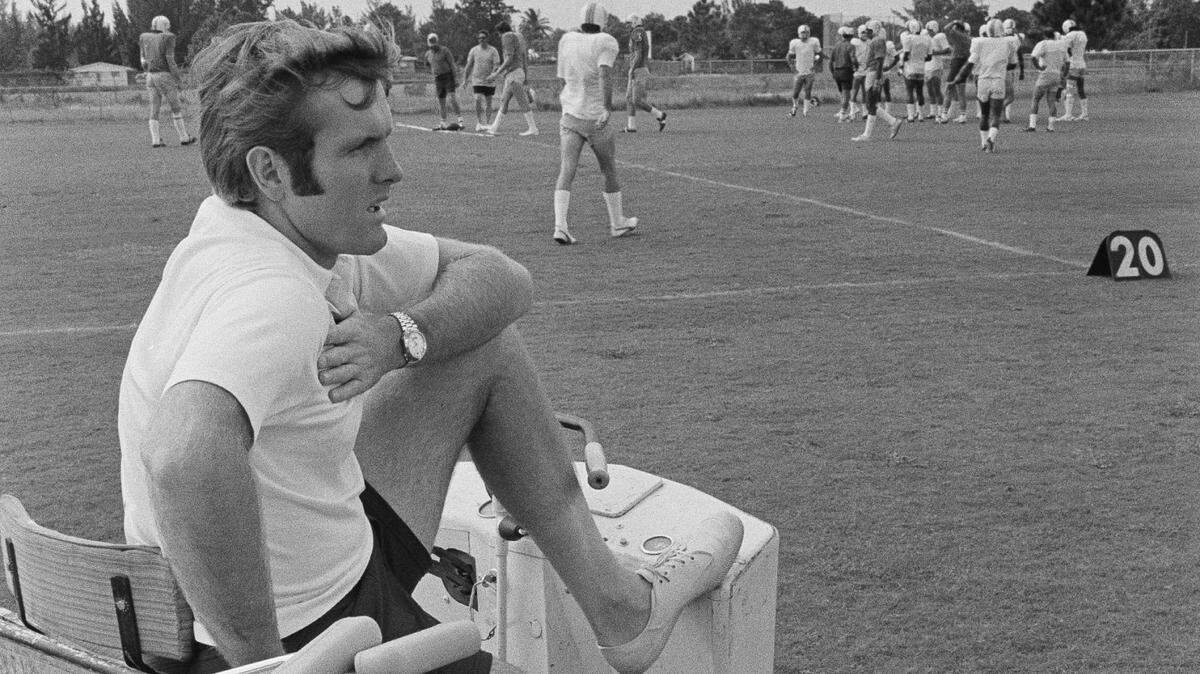 Injured Miami Dolphin quarterback Bob Griese takes on a new role as he watches practice from the sidelines Oct. 21, 1972 in Miami. Griese suffered a dislocation and break of the ankle bone in game with San Diego and is expected to be out of action for 6 to 8 weeks. The Dolphins are the only undefeated team in the NFL going into Sundays game here with the Buffalo Bills. (AP Photo/MTF)
