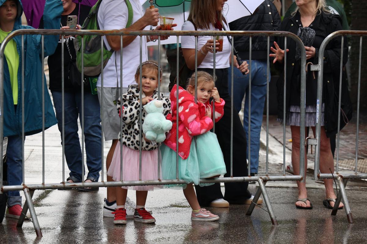 Twins Luna, 4, center-left, Sun Perea, center-right, wait patiently for the start of the parade under the threat of rain. It was singing, dancing, and parading in the rain as Coconut Grove held its annual satirical parade on Sunday, January 7, 2023 in Miami, Florida.