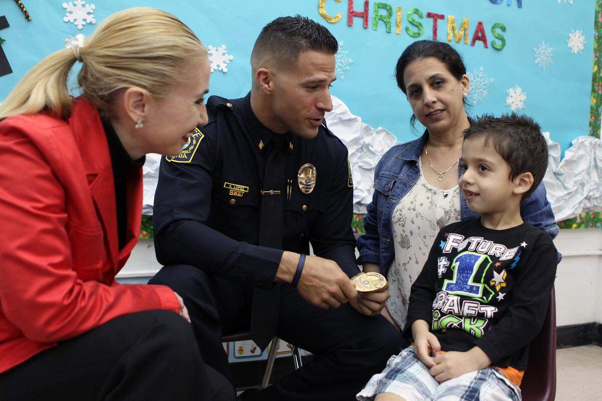 Miami-Dade Police School Commander Edwin Lopez (center left) speaks with Ismary Rey (center right) and her son, Roberto Docina, at a school in December 2015.