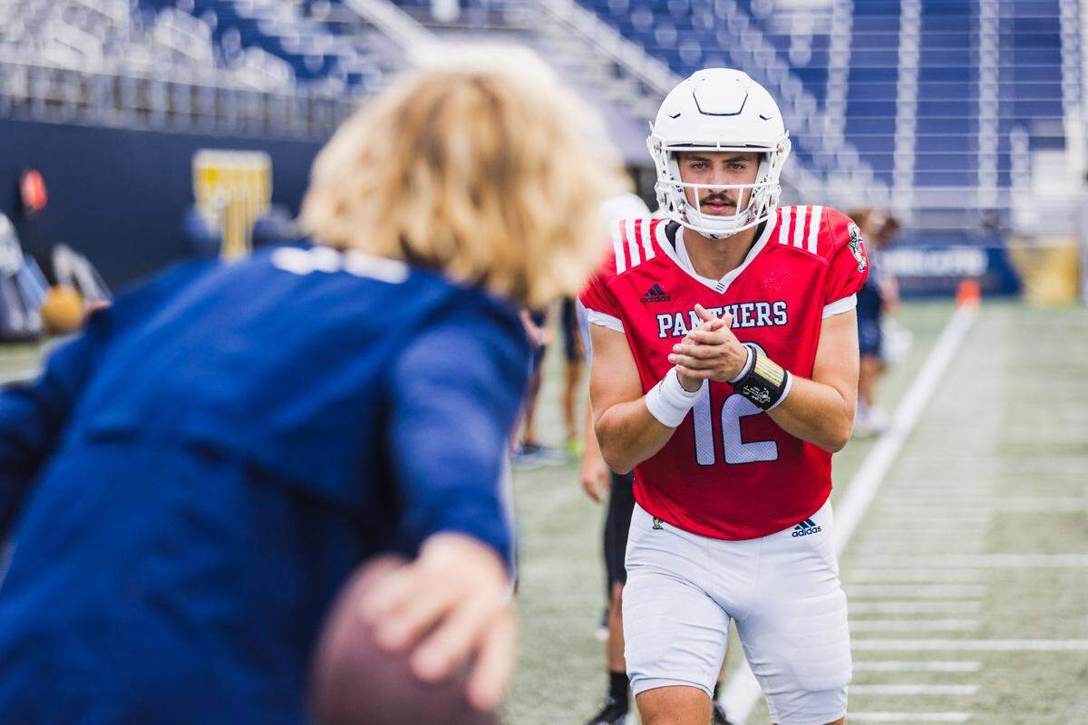 FIU offensive coordinator David Yost tosses the ball to quarterback Gunnar Holmberg during a fall practice session.