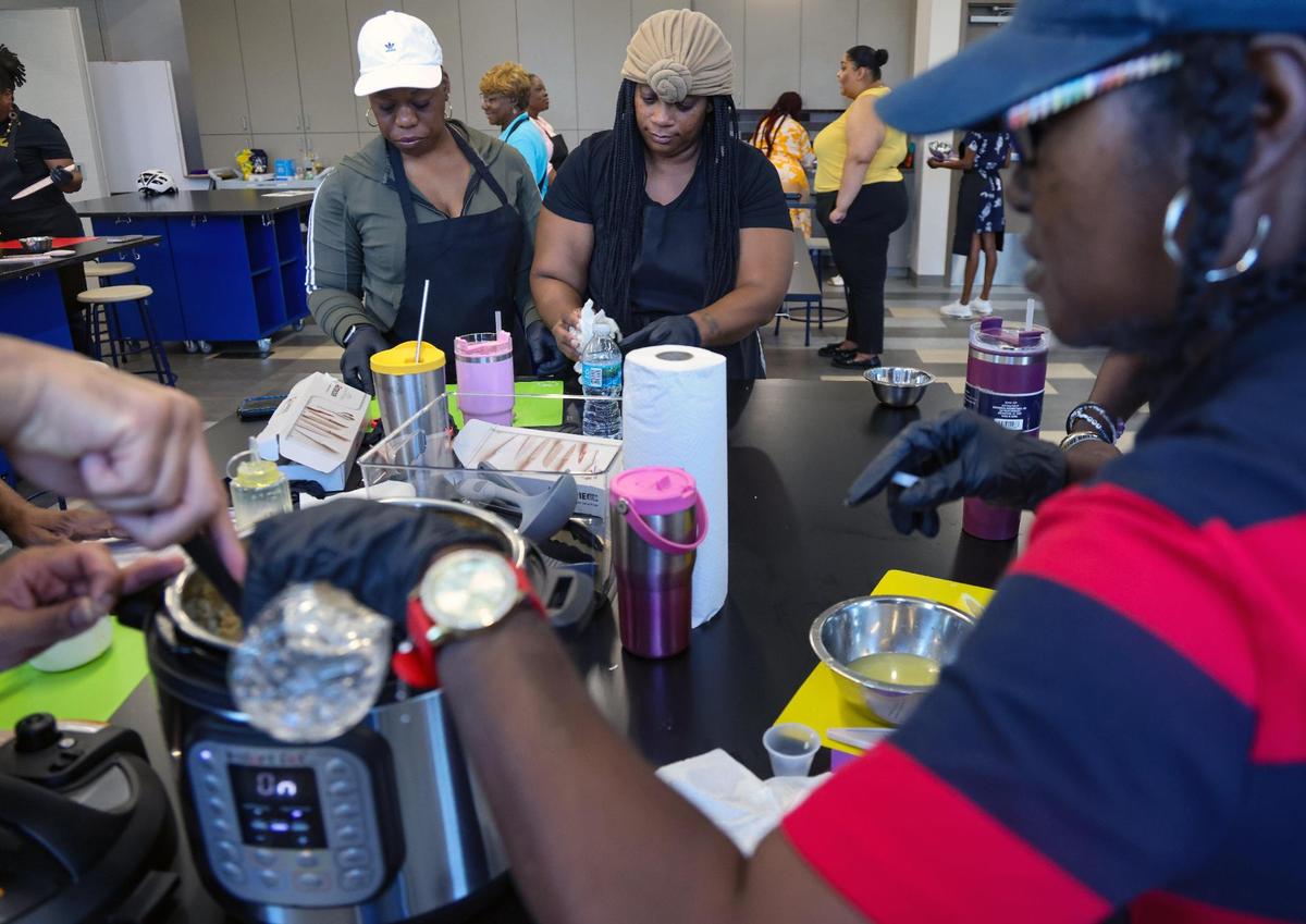 Members of the “No Limit” cooking group Micona Williams, 44, left, Jaimie Garland, 38, and Maeshile Daniels, 56, add the ingredients in the pressure cooker during a cooking pilot program launched by Miami Beach resident and longevity expert Dan Buettner, at the Overtown Youth Center on April 3, 2025, in Miami, Florida.