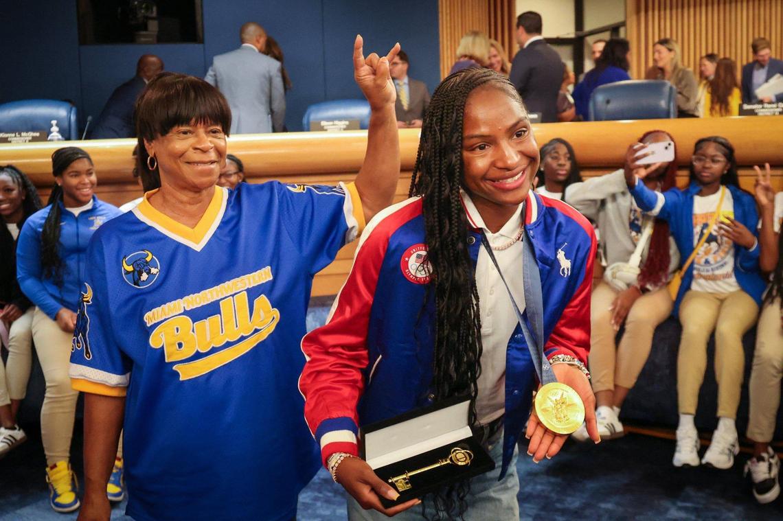 Miami Northwestern High track coach Carmen Jackson, left, shows her Bulls pride with a horns gesture as Twanisha ‘Tee Tee’ Terry, who was coached by Jackson, displays her key to the county and gold medal on Wednesday at Miami-Dade County Commission chamber at the Stephen P. Clark Center in Miami.