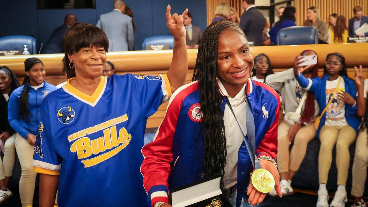 Miami Northwestern High track coach Carmen Jackson, left, shows her Bulls pride with a horns gesture as Twanisha ‘Tee Tee’ Terry, who was coached by Jackson, displays her key to the county and gold medal on Wednesday at Miami-Dade County Commission chamber at the Stephen P. Clark Center in Miami.
