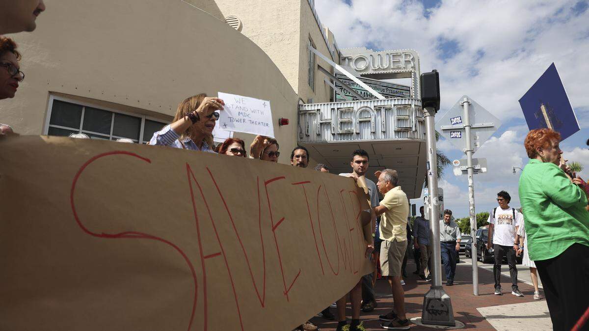 People hold a “Save Tower” sign outside of Tower Theater during the Miami-Dade College Tower Theater protest on Tuesday, Oct. 4, 2022, in Little Havana. 