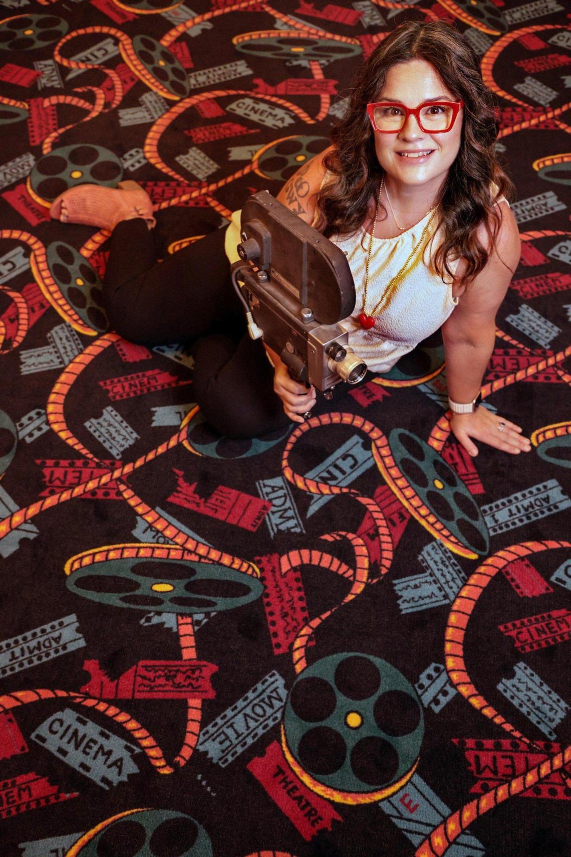 Coral Gables Art Cinema Executive Director Brenda Moe sits on the theater’s new rug in the lobby. The rug was installed while the cinema was closed during the COVID shutdown.