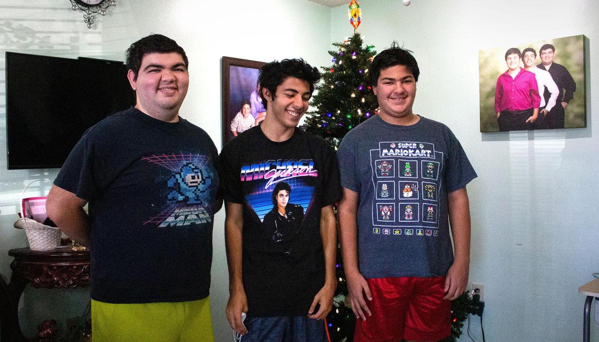 Andres Lorenzo, 22, left, stands with his brothers, Eros, 19, and Xander, 16, right, in their home in Hialeah. Andres and Xander are autistic.