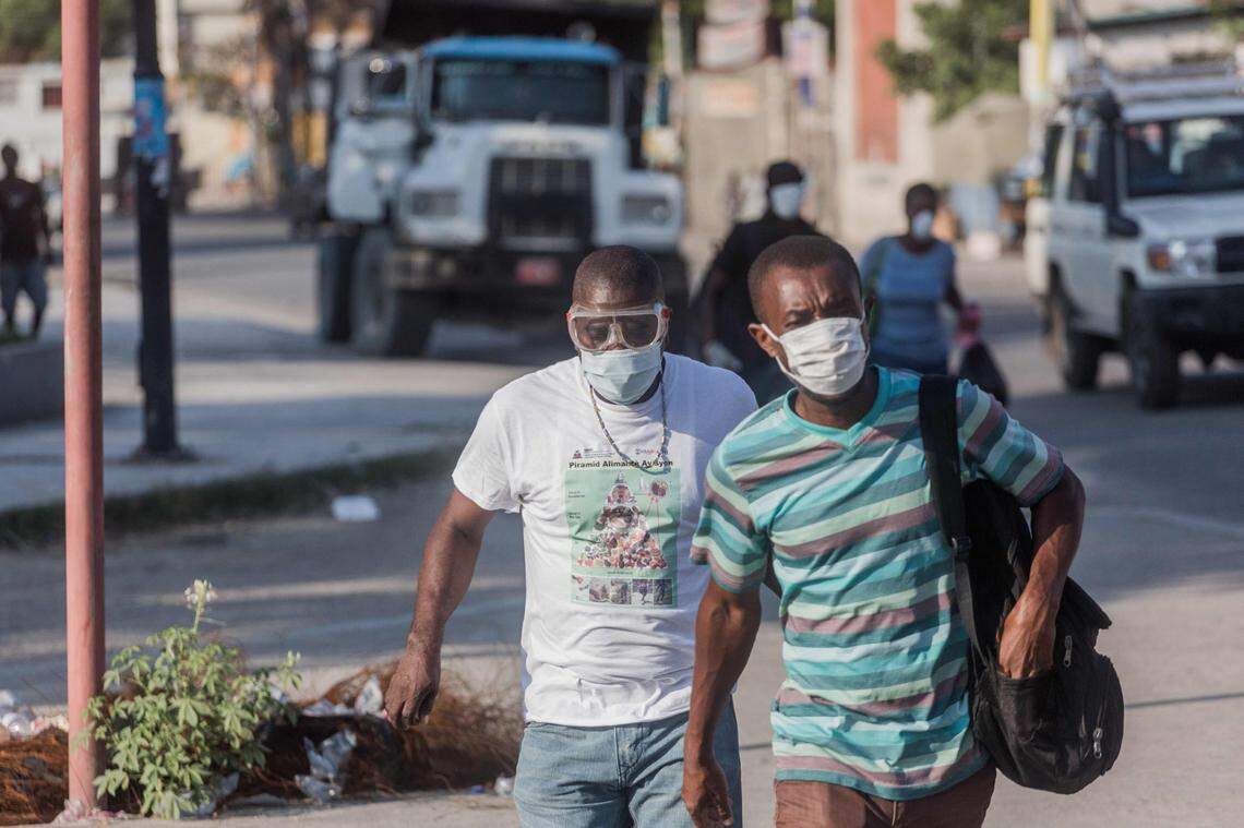 Two men wear masks as they walk in the streets of downtown Port-au-Prince on March 26, 2020.