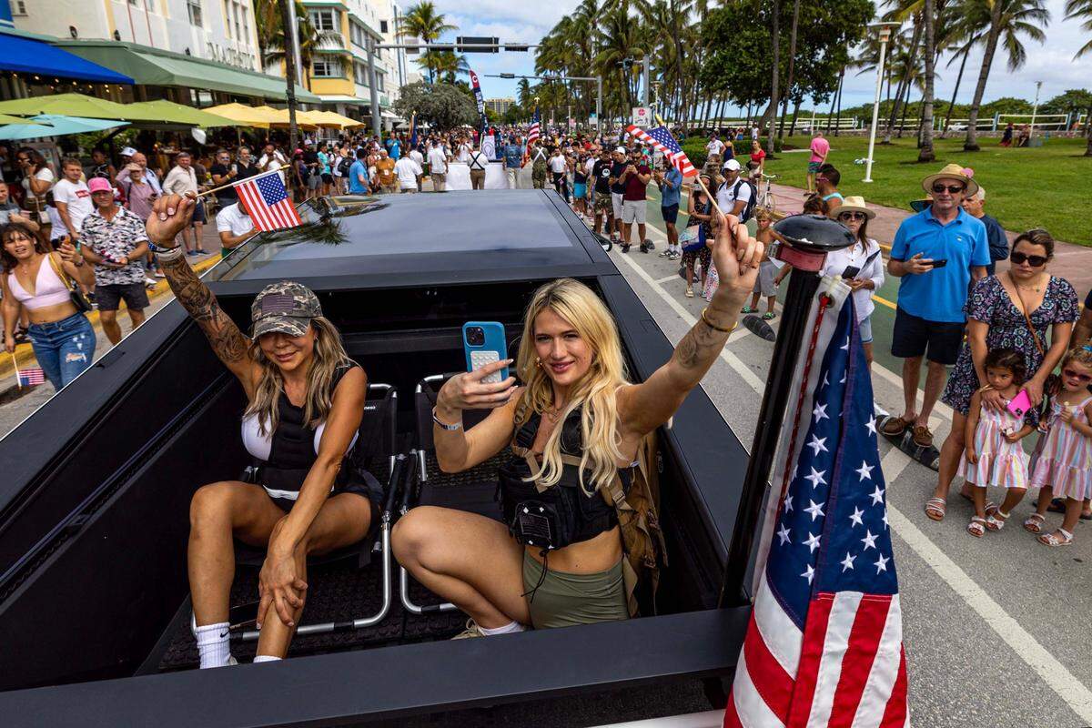 Parade participants wave mini American flags as they are driven down Ocean Drive during the 16th Annual Veterans Day Parade on Monday, Nov. 11, 2024, in Miami Beach, Fla.