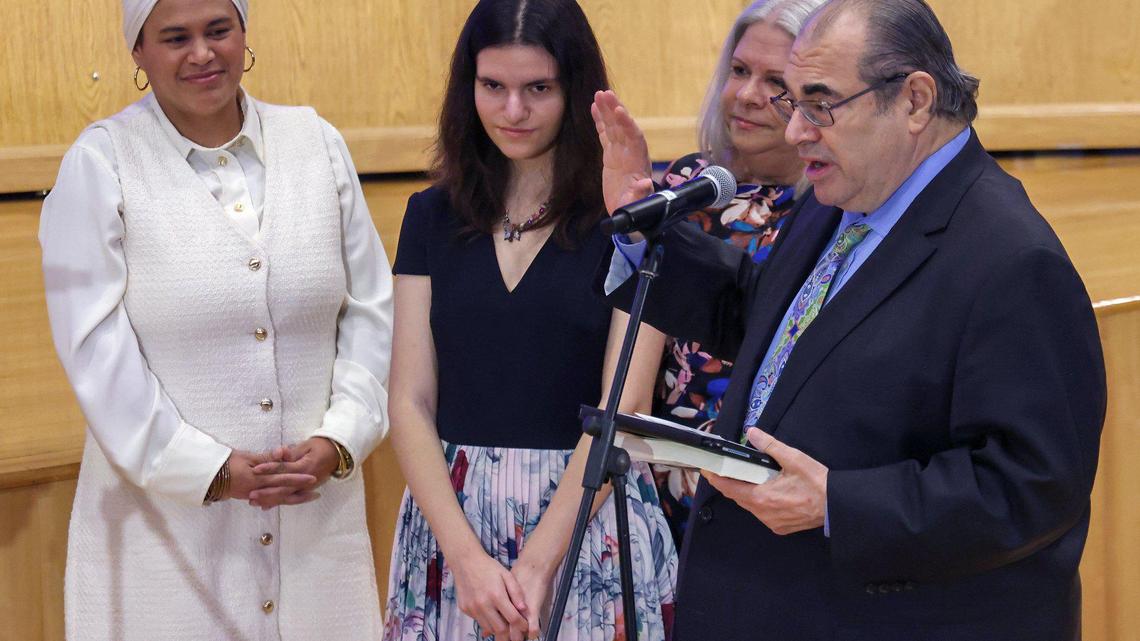 Former school board member Lucia Baez-Geller, left, looks on while Joe Geller, right, takes the oath of office with wife and daughter, center, at his side as five new Miami-Dade County school board members were sworn-in at the Miami-Dade County Administration Building on Tuesday, November 19, 2024 in Miami, Florida.