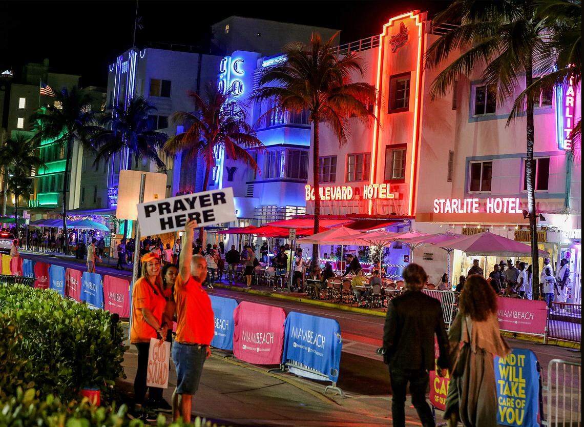 ‘God Squad’s volunteers offer a pray to pedestrians on Ocean Drive Saturday night, March 26, 2022, before the midnight curfew imposed by the City of Miami Beach for the South Beach area, due to two shootings the weekend before that caused city officials to announce a “state of emergency”.
