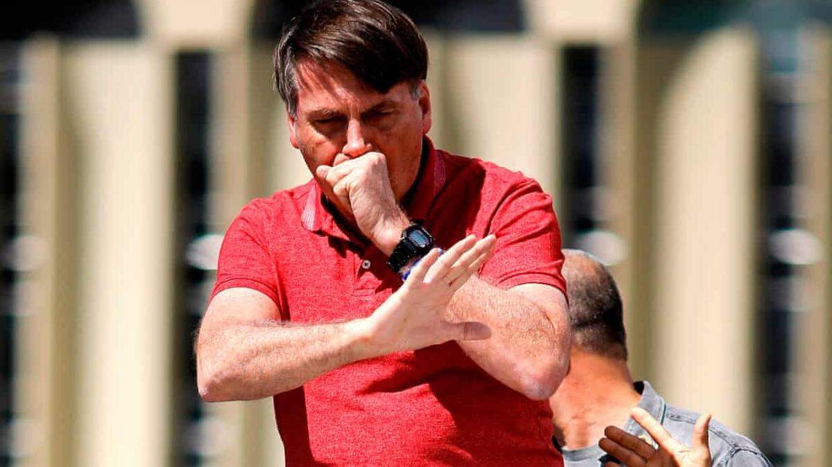 Brazil’s President Jair Bolsonaro coughs as he speaks in Brasília in April 2020. Like President Trump, he downplayed the deadly coronavirus and eventually was infected.