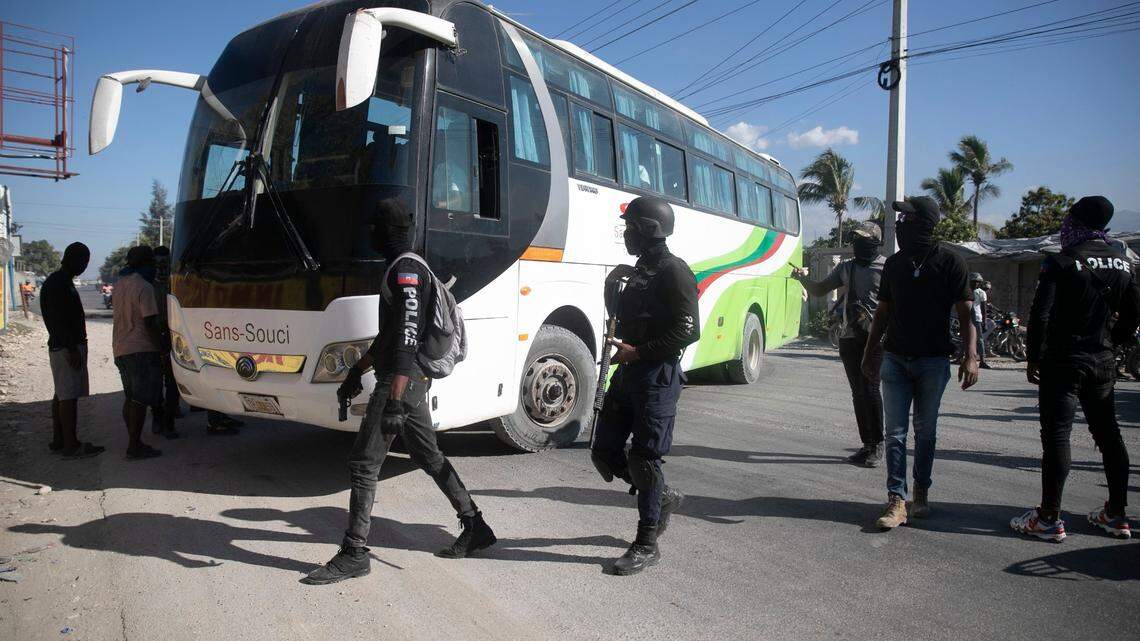 Armed and masked police officers force a driver to park his bus to be used as a barricade during a protest to denounce bad police governance, in Port-au-Prince, Haiti, Thursday, Jan. 26, 2023.