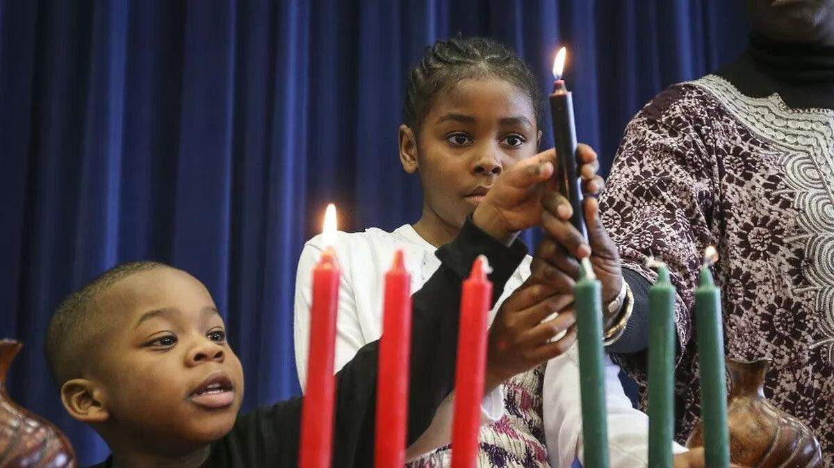 Two children light the “kinara” in celebration of Kwanzaa.