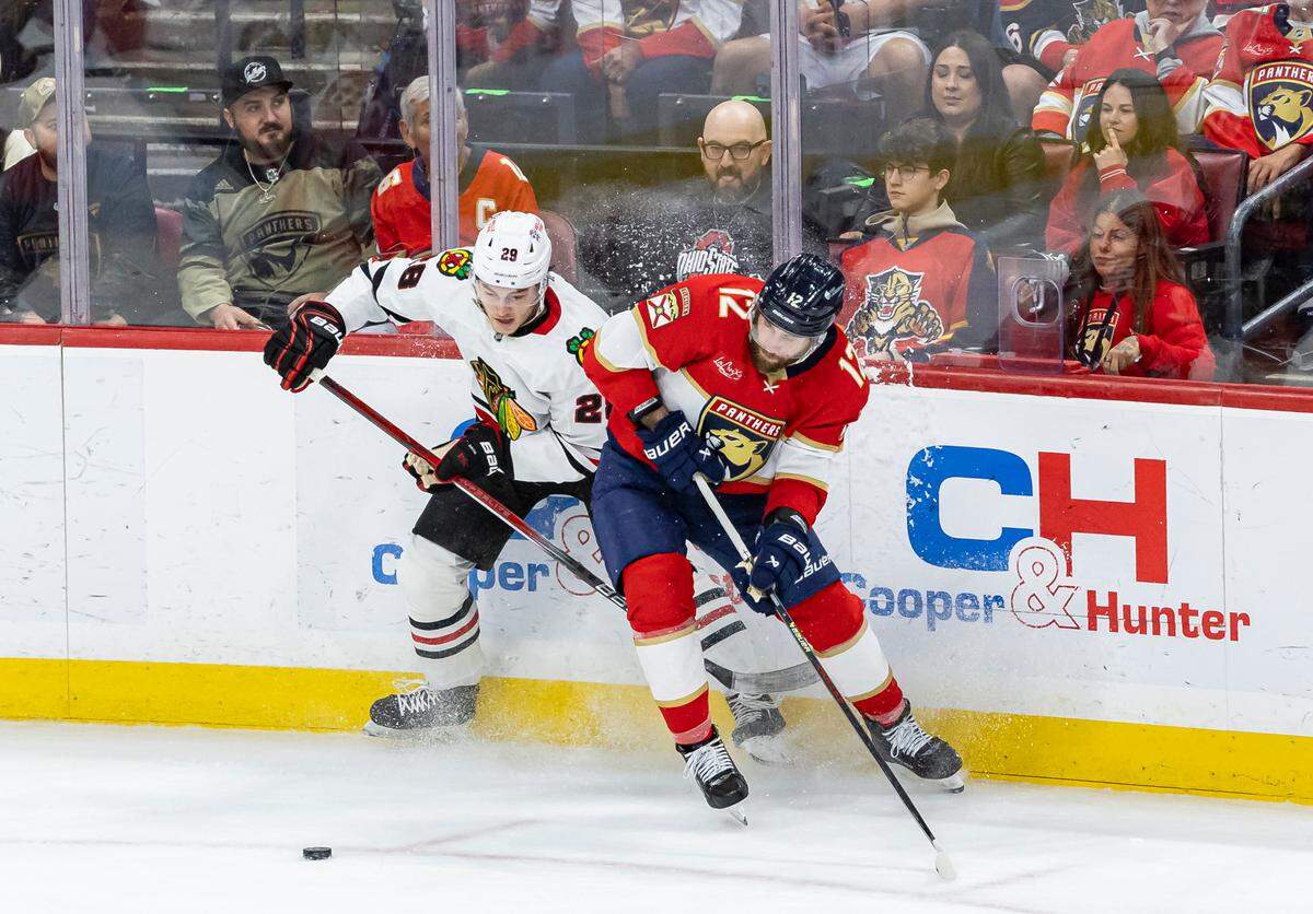 Florida Panthers left wing Jonah Gadjovich (12) and Chicago Blackhawks center Colton Dach (28) compete for the pick in the second period of their NHL game at Amerant Bank Arena on Saturday, Feb. 1, 2025, in Sunrise, Fla.