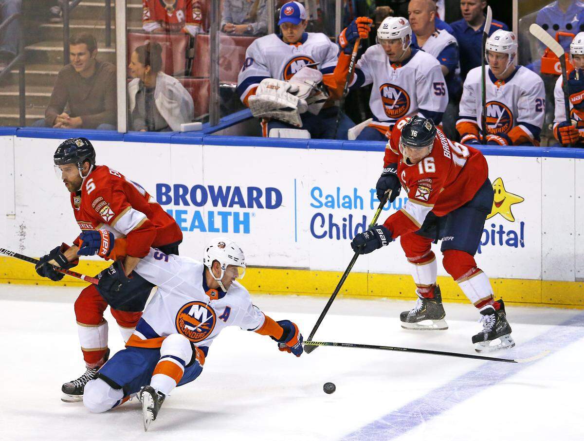 Florida Panthers center Aleksander Barkov (16) and Aaron Ekblad (5) battle for a puck against New York Islanders right wing Cal Clutterbuck (15) during the third period&nbsp;of an NHL regular season hockey game at the BB&T Center on Thursday, December 12, 2019 in Sunrise.