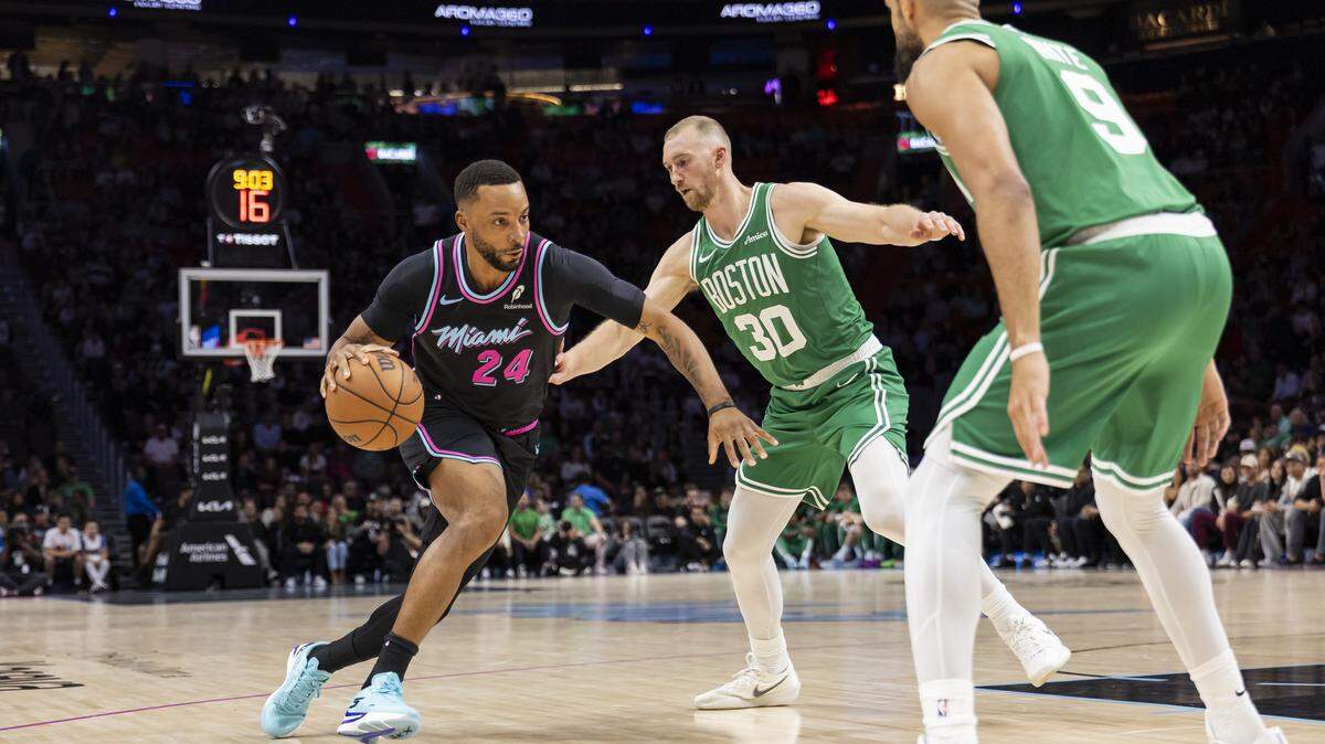 Miami Heat guard Norman Powell (24) drives the ball as Boston Celtics forward Sam Hauser (30) and guard Derrick White (9) defend in the first half of their NBA game at Kaseya Center on Jan. 15, 2026, in Miami.