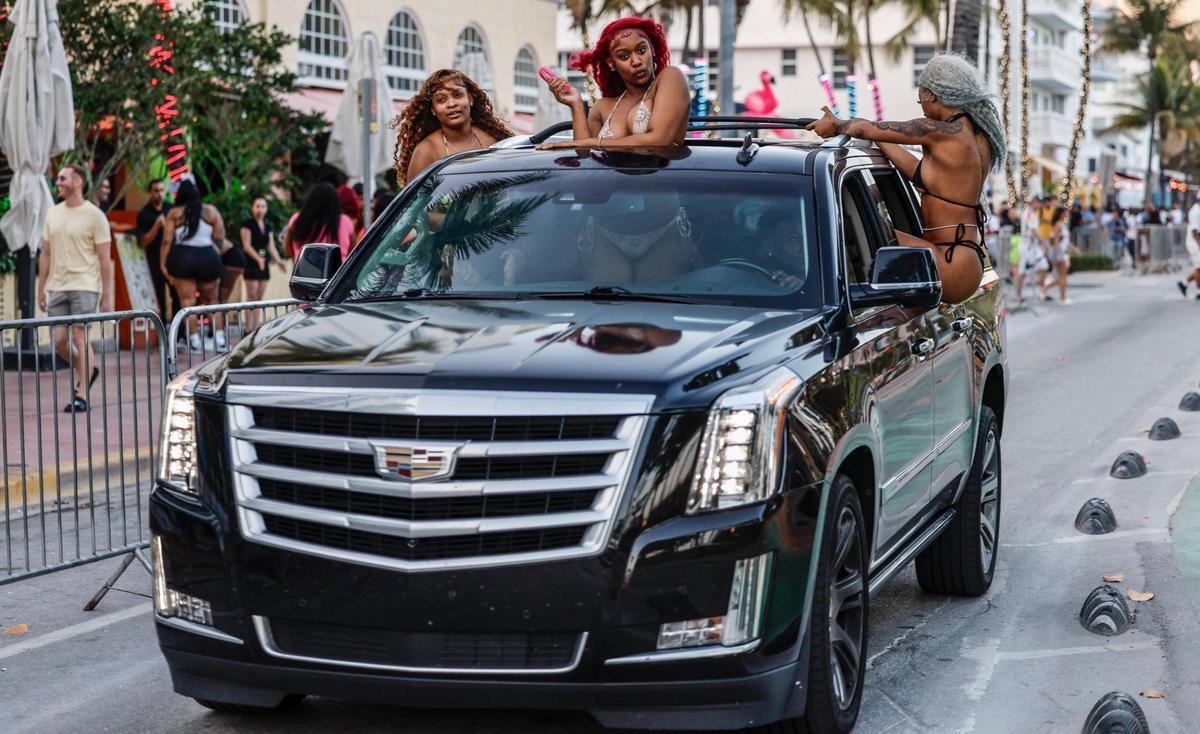 Spring breakers hang and dance out of a Cadillac Escalade along Ocean Drive in Miami Beach, Florida on Saturday, March 15, 2025.