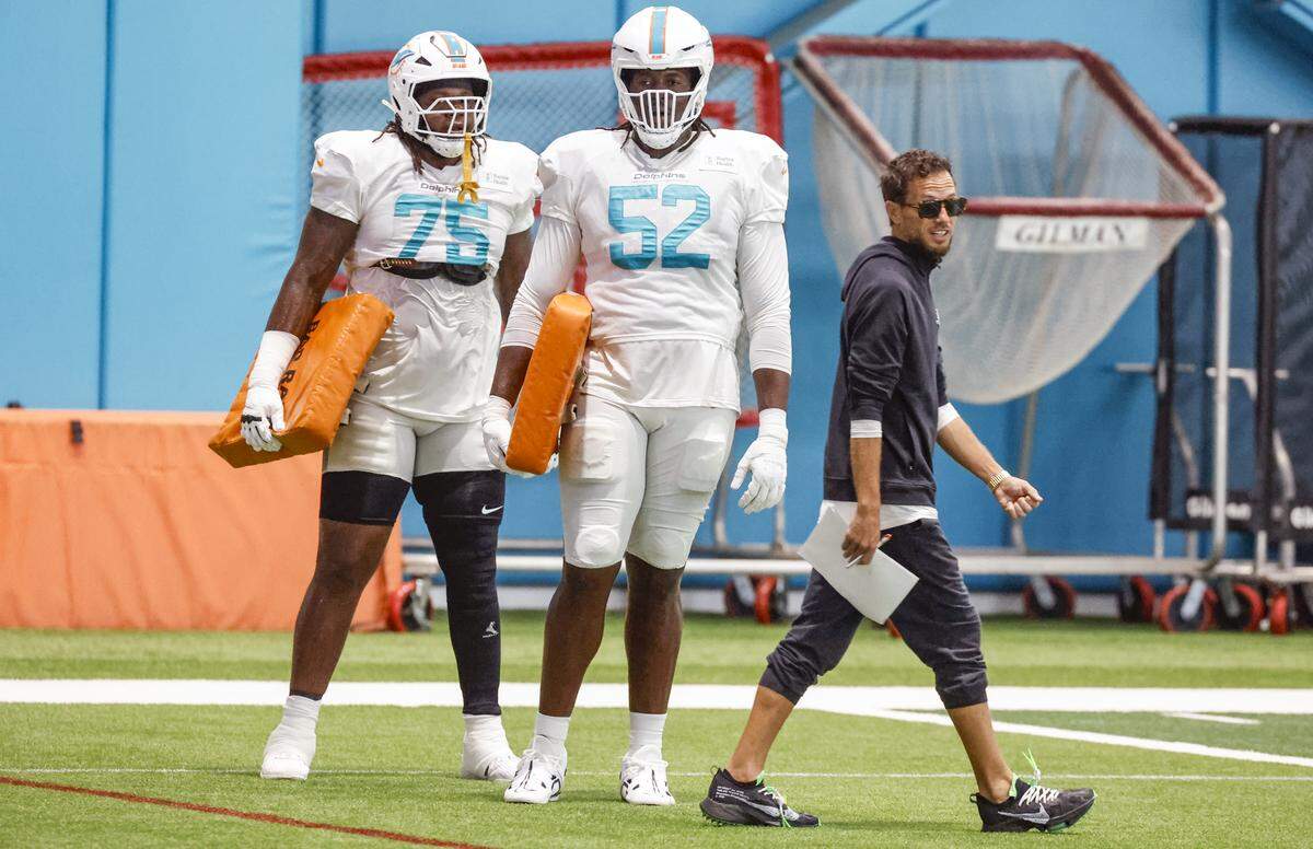 Miami Dolphins coach Mike McDaniel walks pass offensive lineman Jalen McKenzie (75) and Patrick Paul (52) during practice at the Miami Dolphins Training Camp in Miami Gardens, Florida, on Wednesday, August 20, 2025.