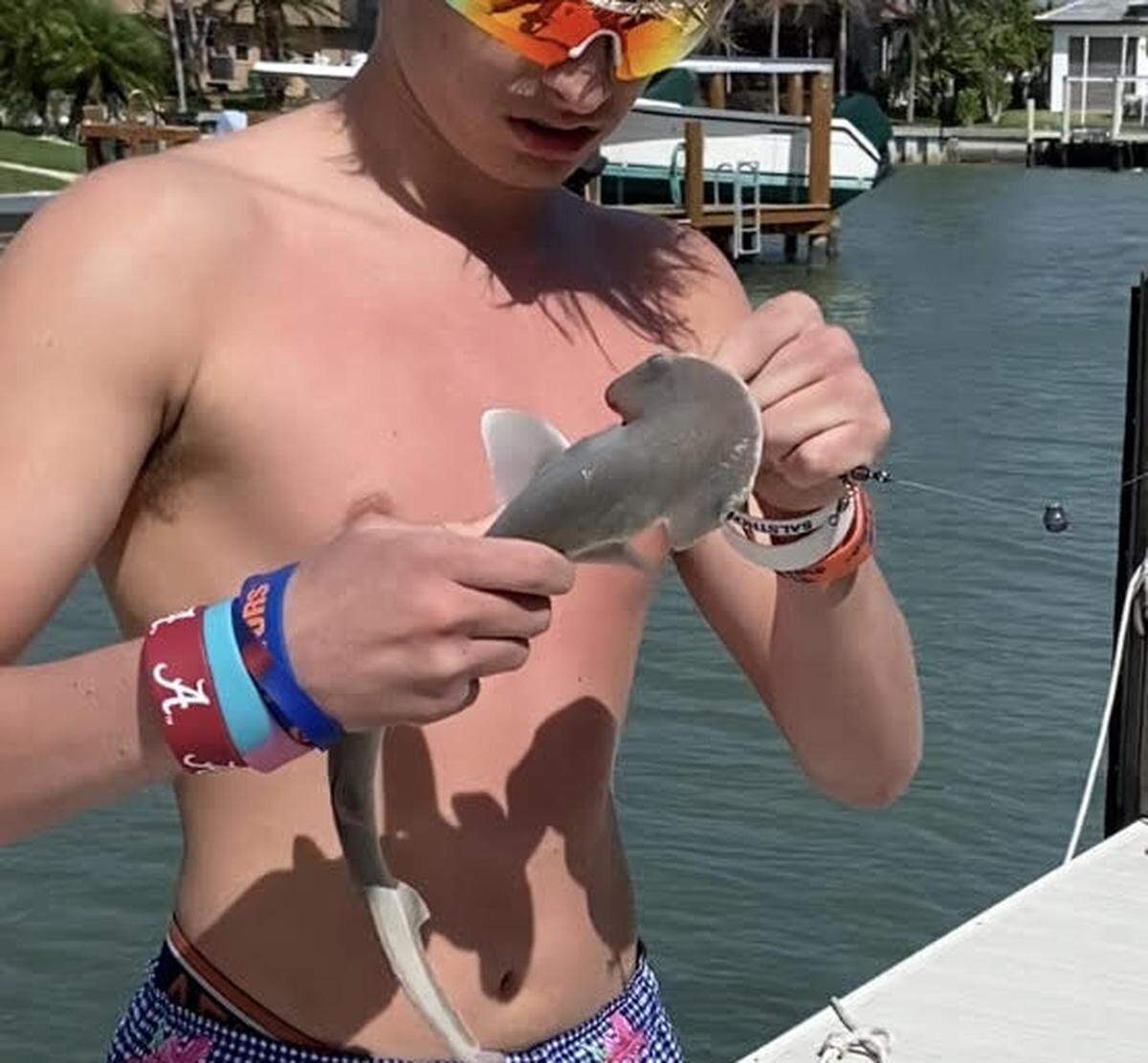 Un adolescente retira un anzuelo de la boca de un tiburón bonete antes de liberarlo de nuevo en un canal en Marco Island el domingo 12 de febrero de 2023.