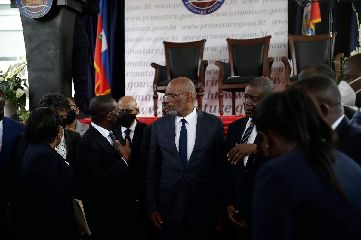 New Prime Minister Ariel Henry, center, talks with former interim Prime Minister Claude Joseph as they stand surrounded by Henry’s cabinet after his appointment in Port-au-Prince, Haiti, Tuesday, July 20, 2021, weeks after the assassination of President Jovenel Moise at his home.