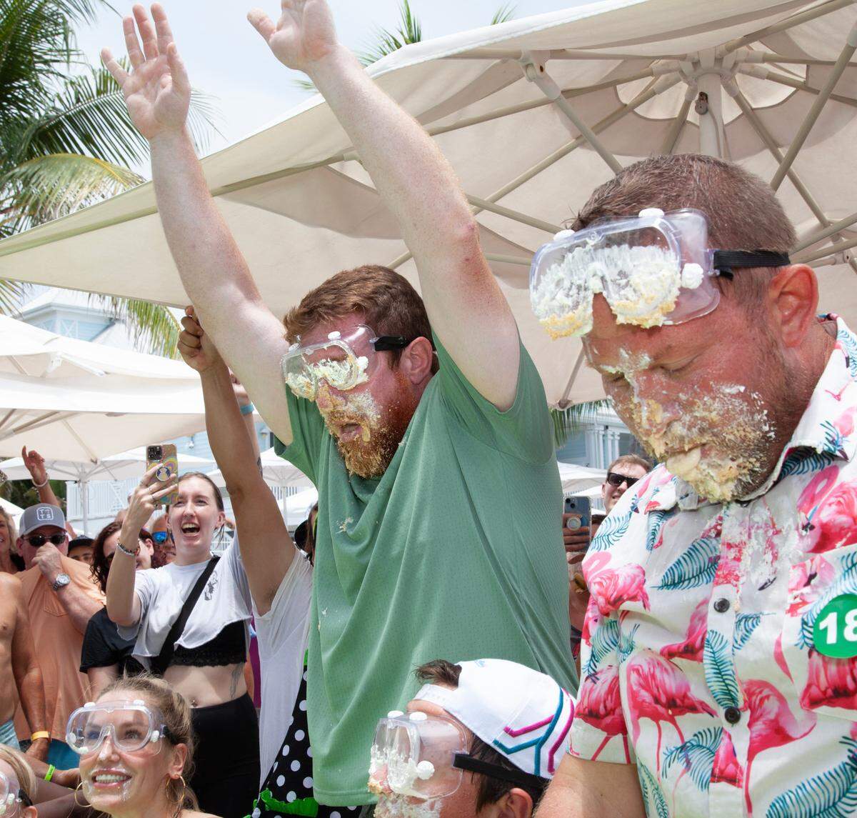 Joshua Mogle, left, of Altoona, Iowa, raises his hands to signify that he has finished devouring a 9-inch Key lime pie at the World Famous Key Lime Pie Eating Championship Tuesday, July 4, 2023, in Key West.