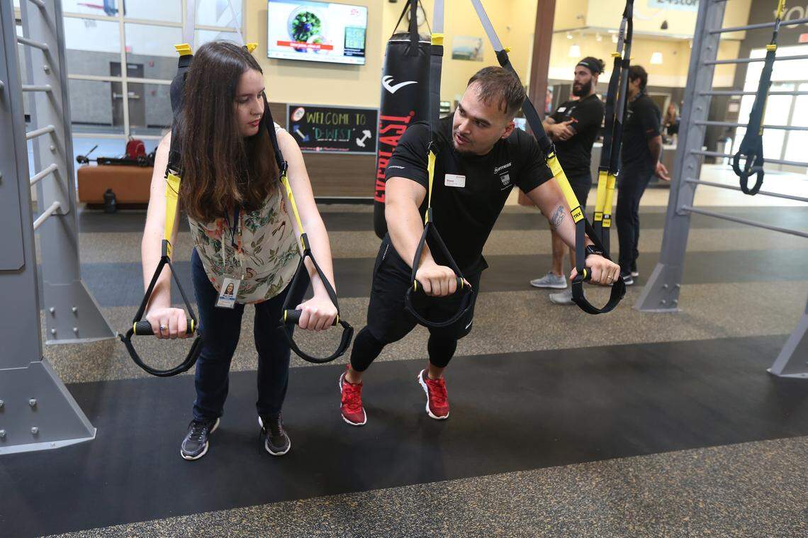 24 Hour Fitness Master Trainer, Orlando Lopez, guides Michelle Marchante, a Miami Herald reporter, through a TRX bench press workout (recommended for beginners) at the new gym at 1970 NW 117th Pl. in Miami on January 31, 2020.