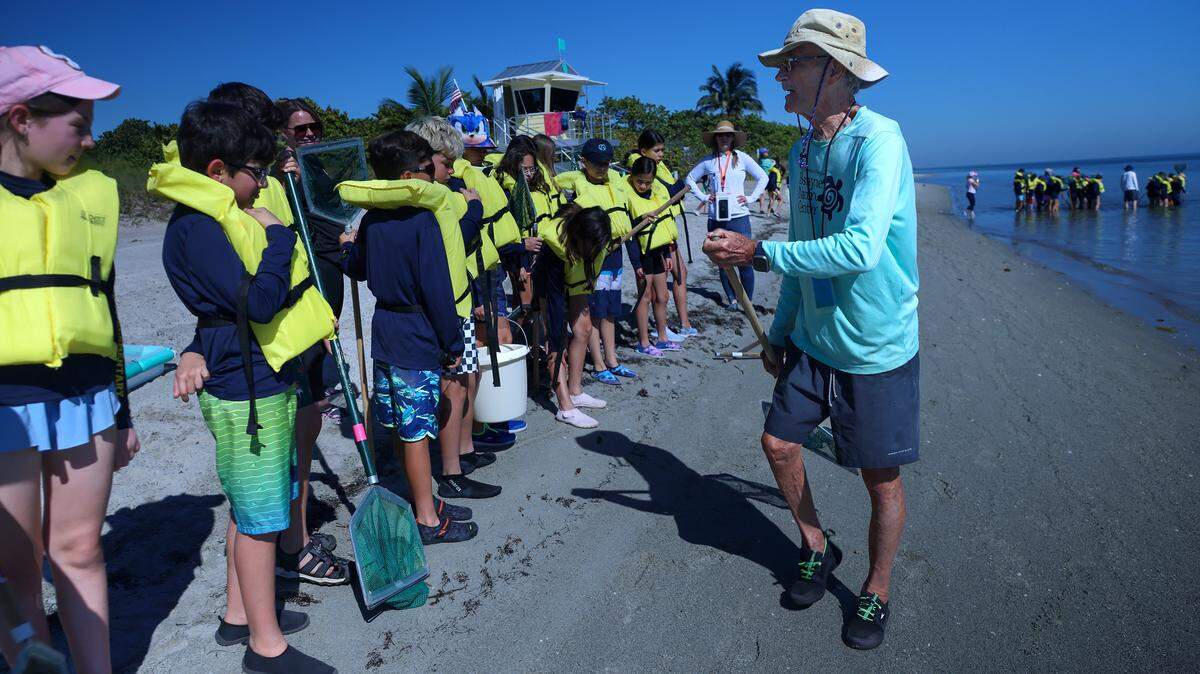Naturalist David Mikolashek, right, demonstrates how to use the nets to “catch-and-release” marine animals living in sea grass to Pinecrest Elementary students at Crandon Park's Marjory Stoneman Douglas Biscayne Nature Center on Tuesday, November 17, 2025, in Key Biscayne, Florida.