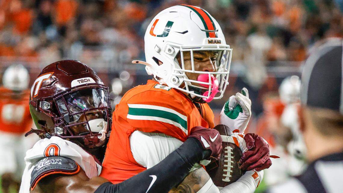 Miami Hurricanes tight end Elijah Arroyo (8) on a long pass reception as Virginia Tech Hokies linebacker Keli Lawson (0) defends during the first half of an ACC conference football game at Hard Rock Stadium on Friday, September 27, 2024, in Miami Gardens, Fla.