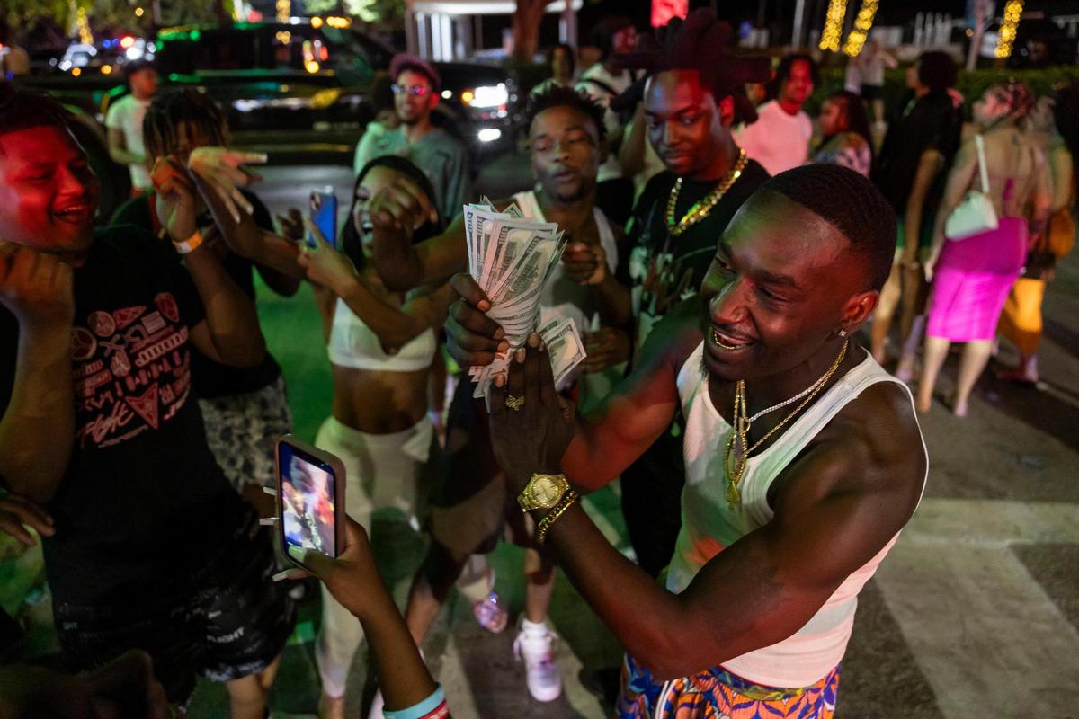 A man flashes cash while recording a video on Ocean Drive during spring break on Friday, March 15, 2024, in Miami Beach.&nbsp;